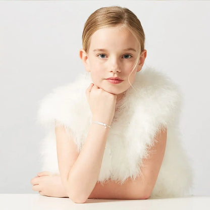 Young girl wearing a white feathered garment against a plain background